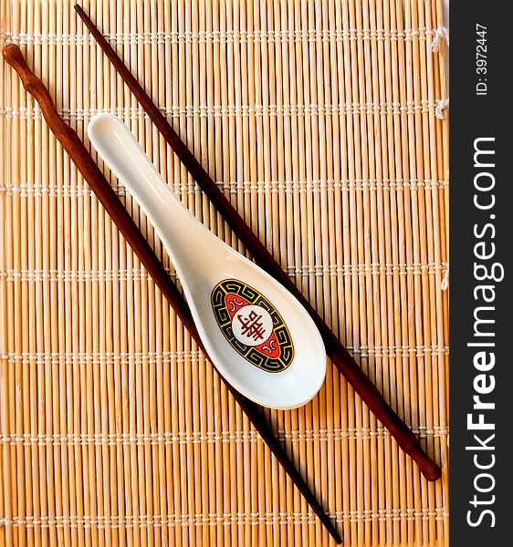 A  soup spoon and chopsticks on bamboo used for rolling sushi. A  soup spoon and chopsticks on bamboo used for rolling sushi.