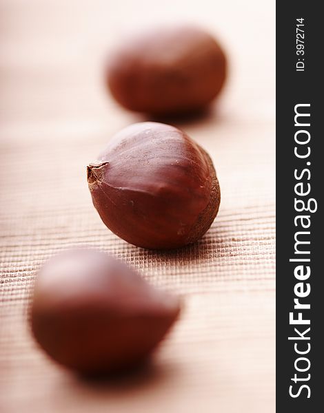 Chesrnuts lined up on cloth, focus on the middle one. Chesrnuts lined up on cloth, focus on the middle one