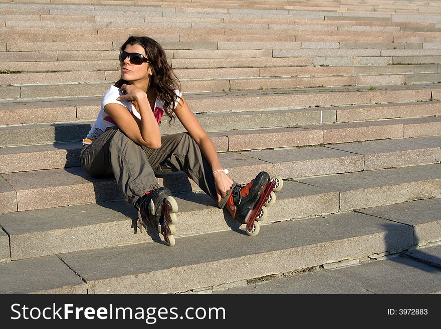 Roller girl sitting at stairs at sunny day. Roller girl sitting at stairs at sunny day.