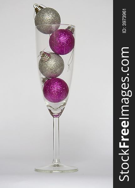 Four purple and silver Christmas baubles in a champagne glass