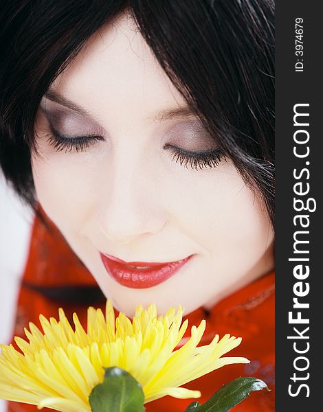 Close-up portrait of brunette with white skin smelling yellow flower. Close-up portrait of brunette with white skin smelling yellow flower