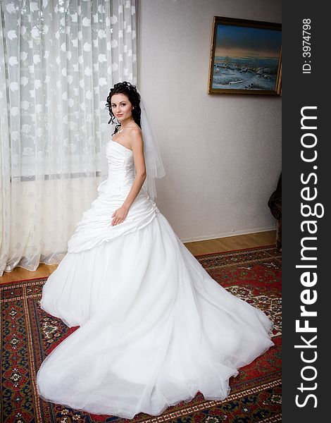 A beatiful bride in a long white dress by the window. A beatiful bride in a long white dress by the window