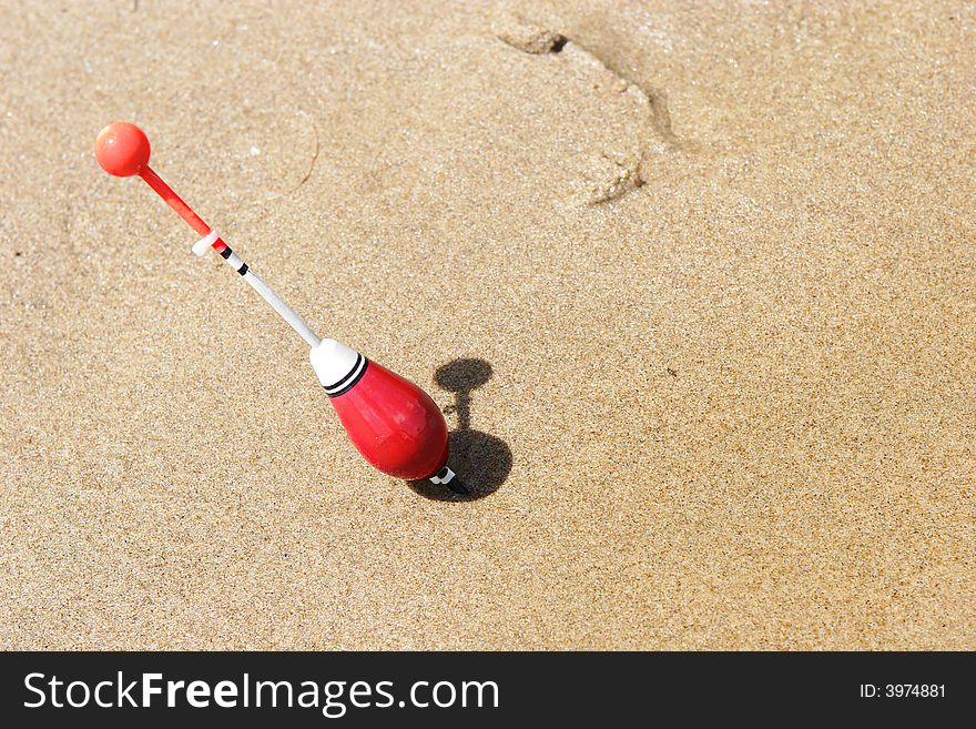 A Fishing Float Sticked Into The Sand