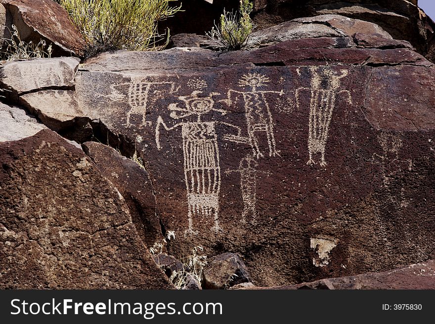 Native American rock art petroglyph of several anthropomorphic like figures carved into desert varnish covered rock in Little Petroglyph Canyon of the Coso Range in California. Native American rock art petroglyph of several anthropomorphic like figures carved into desert varnish covered rock in Little Petroglyph Canyon of the Coso Range in California