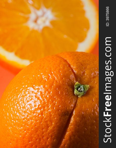 Vertical photo of whole orange in foreground with sliced orange in background. Vertical photo of whole orange in foreground with sliced orange in background