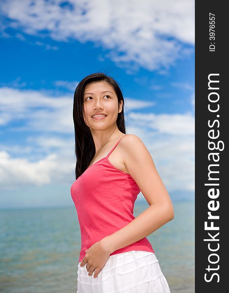 Woman smiling looking far with red top and white skirt stand by the sea. Woman smiling looking far with red top and white skirt stand by the sea