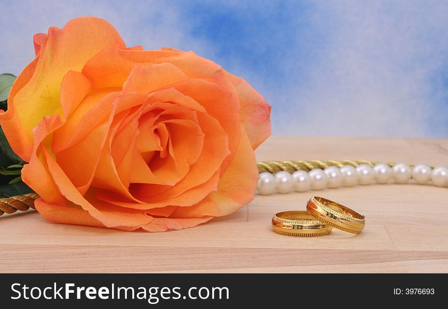 Rose With Wedding Rings and Pearls on Blue Background. Rose With Wedding Rings and Pearls on Blue Background