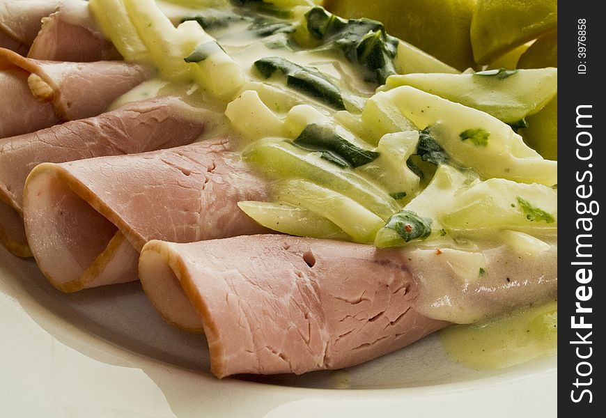 Coked ham rolls with stem cabbage on a white plate