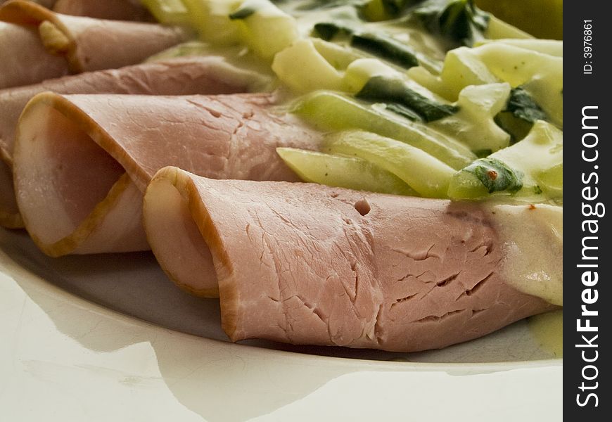 Coked ham rolls with stem cabbage on a white plate