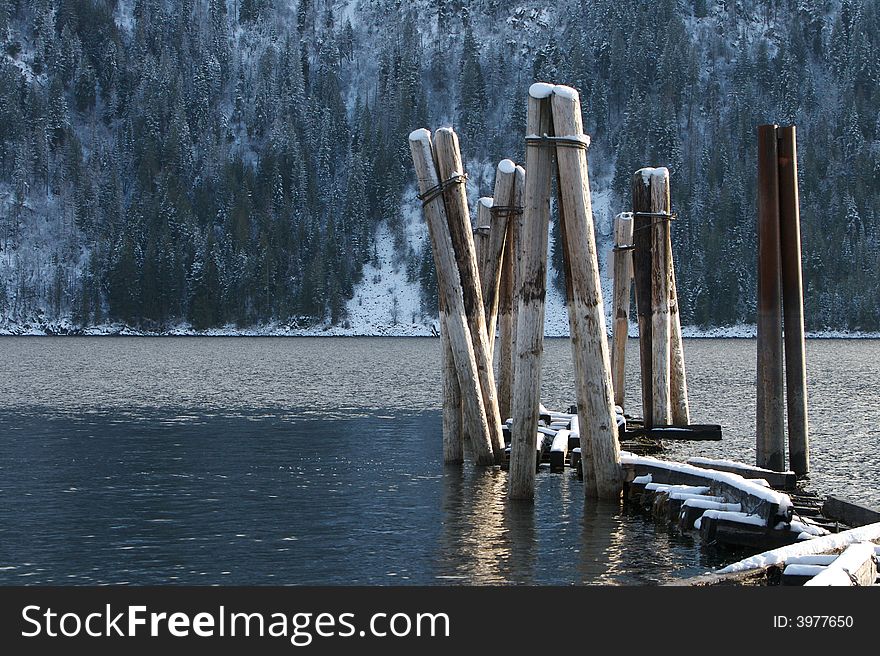 Old boat dock pilings dusted with snow in a mountain lake. Horizontal frame. Old boat dock pilings dusted with snow in a mountain lake. Horizontal frame.