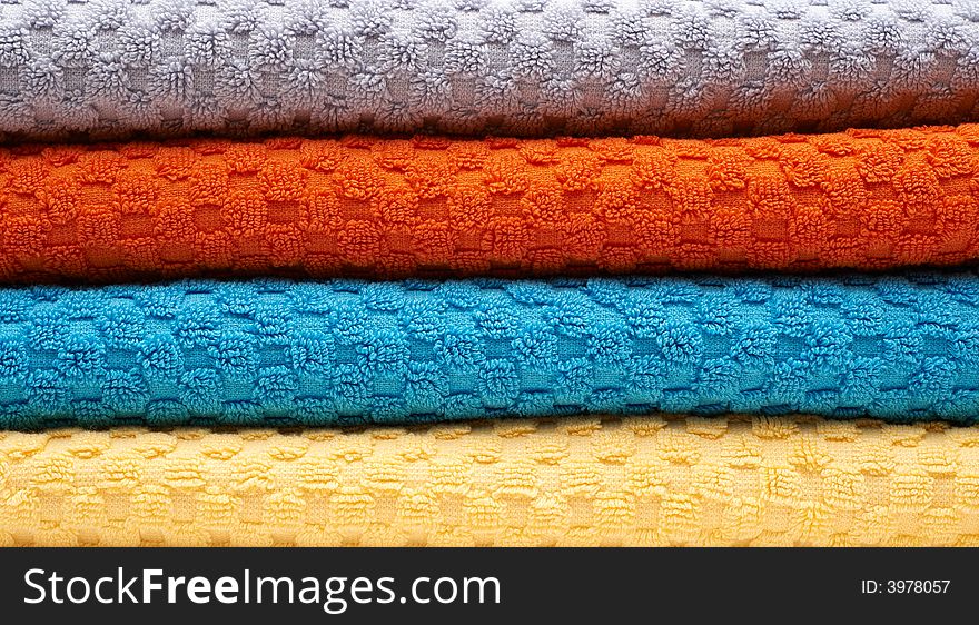 Multicolour towels rolls: gray, orange, blue, yellow. Close-up. Multicolour towels rolls: gray, orange, blue, yellow. Close-up.