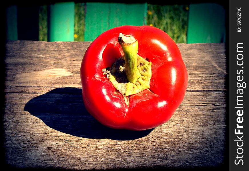 Big red pepper bell on wooden table.
