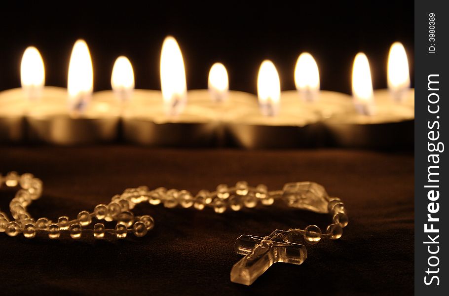 A crucifix in front of a row of candles. A crucifix in front of a row of candles