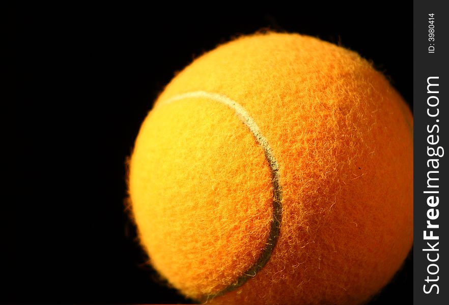 Orange tennis ball on black background