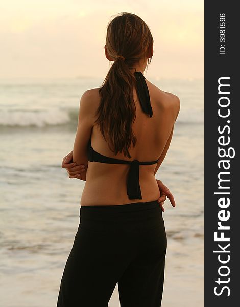 Relaxed woman standing at the beach by sunset. Relaxed woman standing at the beach by sunset
