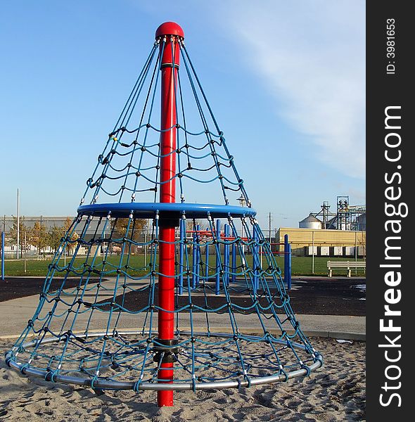 A children's climber in a park with industry in the background. A children's climber in a park with industry in the background.