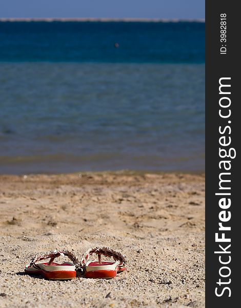 Slippers on the beach. sand and blue water