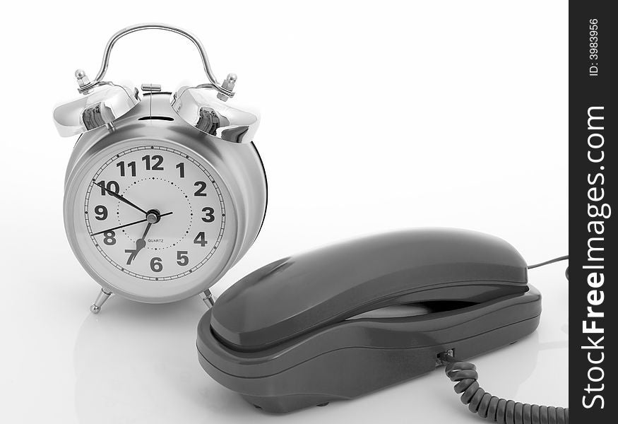 Photo of a telephone and an alarm clock over a white background. Photo of a telephone and an alarm clock over a white background