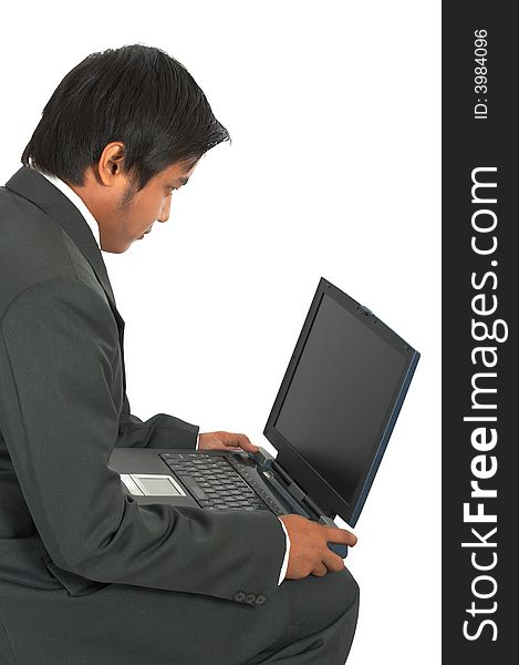 A man sitting while working on his laptop computer