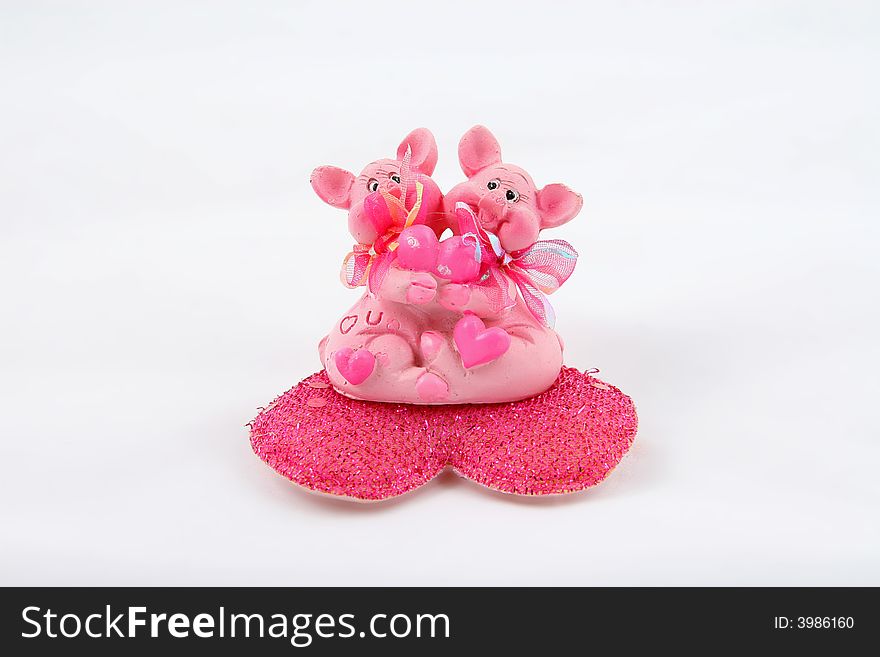 Two pink pigs sitting on heart and holding heart