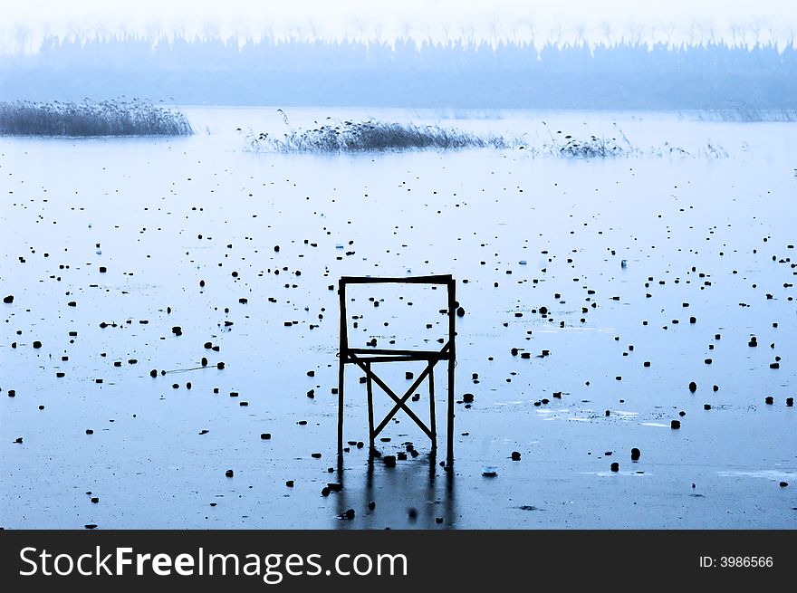 A chair on frozen misty lake. A chair on frozen misty lake