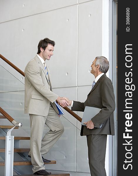 Two businessmen shaking hands on steps