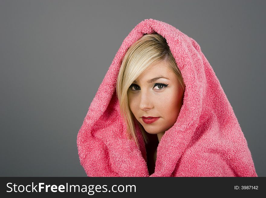 A blonde model in pink towel on grey background. A blonde model in pink towel on grey background