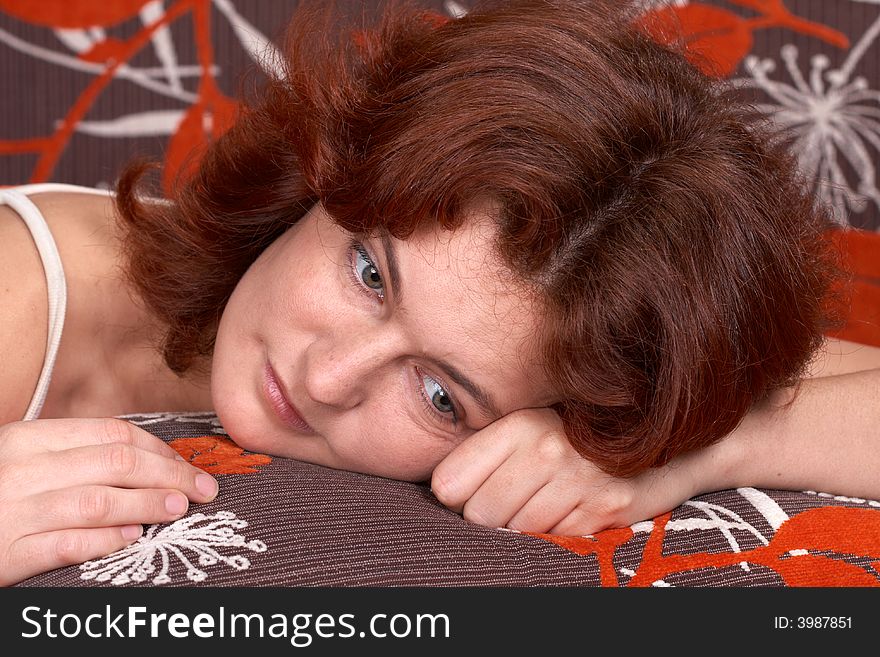 Redheaded girl lying on orange sofe and dreaming. Redheaded girl lying on orange sofe and dreaming