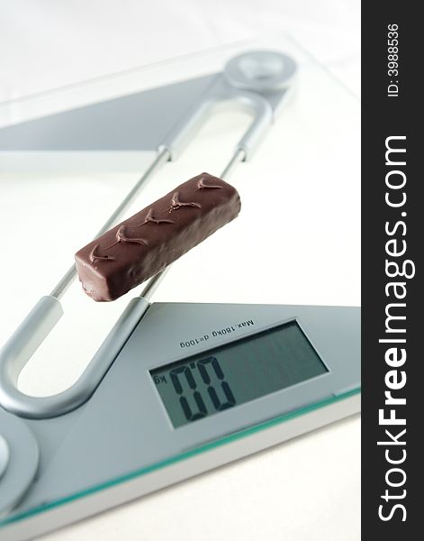 Chocolate bar on the electronic balance showing 0.0kg, methaphore of diet candies. Chocolate bar on the electronic balance showing 0.0kg, methaphore of diet candies