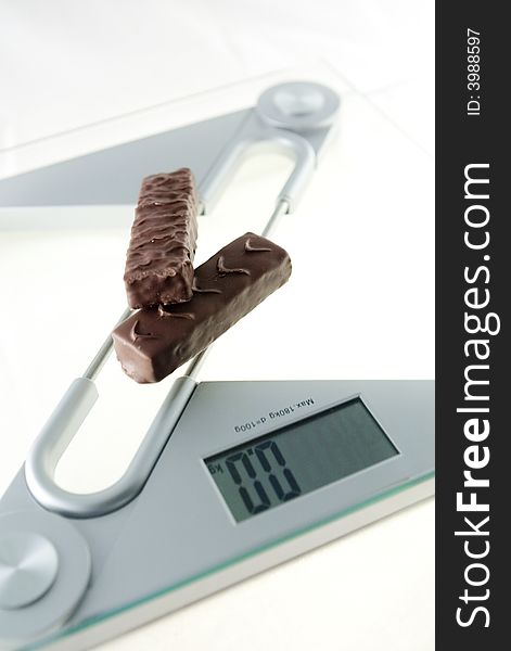 Chocolate bar on the electronic balance showing 0.0kg, methaphore of diet candies. Chocolate bar on the electronic balance showing 0.0kg, methaphore of diet candies