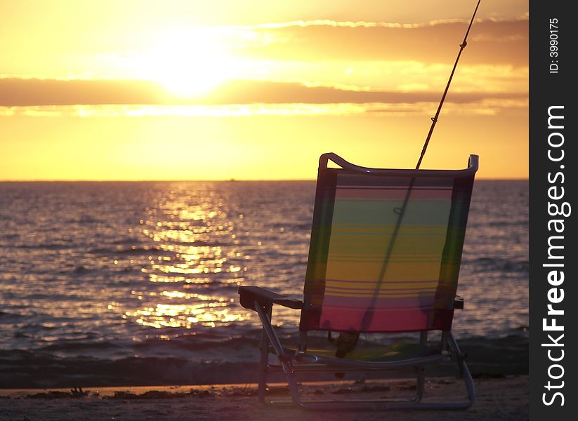 Fishing pole and beach chair at sunset