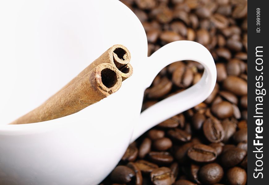 White cup, coffee beans and cinnamon sticks. White cup, coffee beans and cinnamon sticks