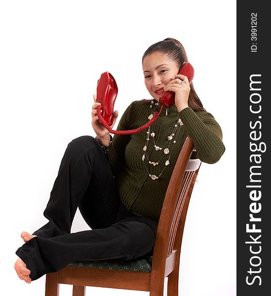 A young female talking on the phone while sitting on the chair. A young female talking on the phone while sitting on the chair