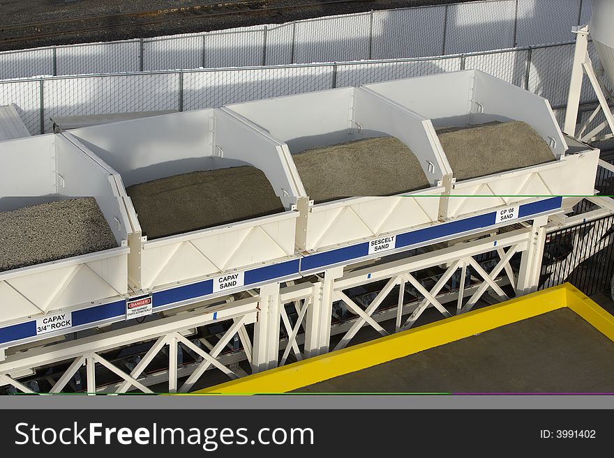 Bins of rock that drop onto a conveyer belt underneath and into the mixing machine. Bins of rock that drop onto a conveyer belt underneath and into the mixing machine