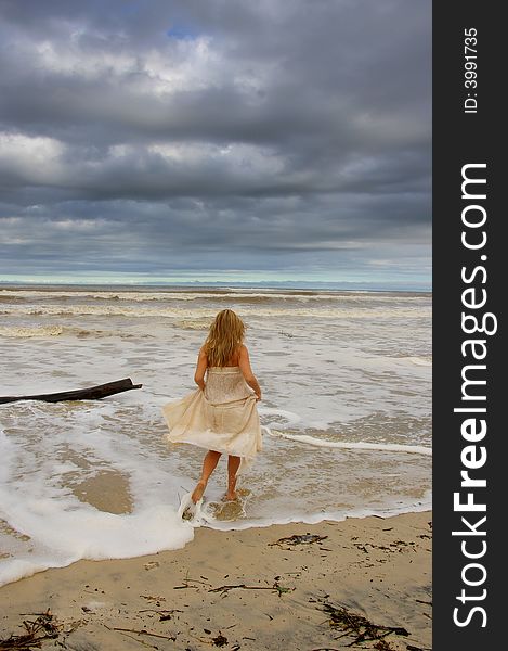 Beautiful girl at the stormy beach walkingwith the wind in her hair