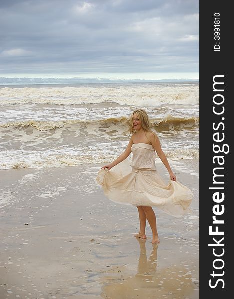 Beautiful girl at the stormy beach walking with the wind in her hair