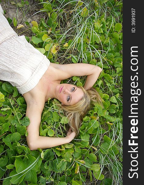 Beautiful girl lying in the grass at the beach. Beautiful girl lying in the grass at the beach