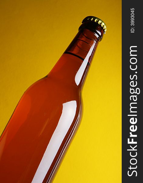 Beer bottle close-up over yellow background. Beer bottle close-up over yellow background