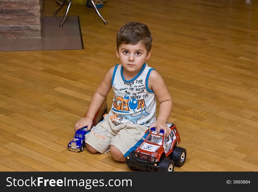 The Little Boy Sitting On A Floor With Toys