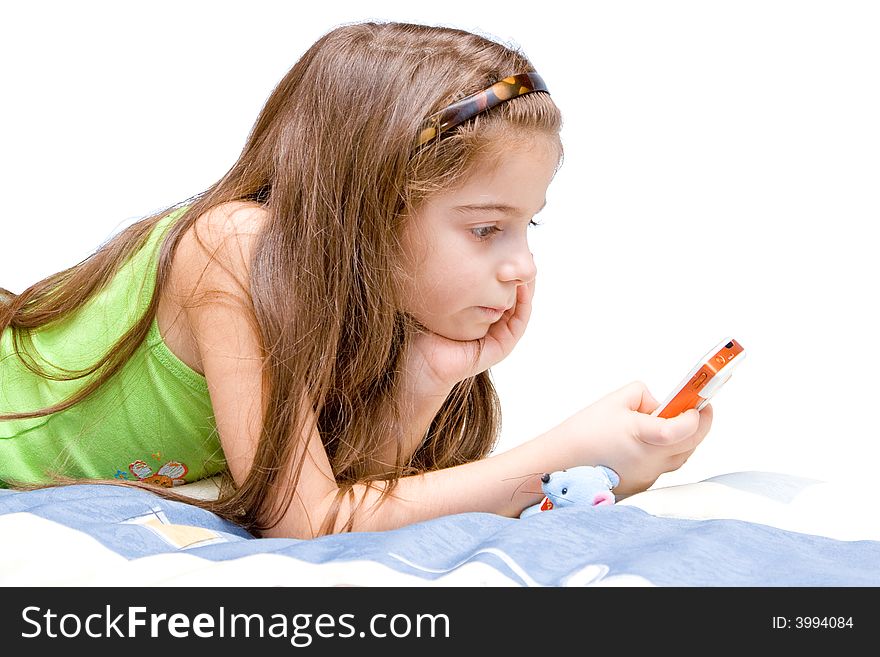 The girl lays on a bed and holds phone.