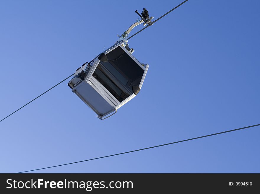 Gondola ski lift on cable with clear sky background. Gondola ski lift on cable with clear sky background