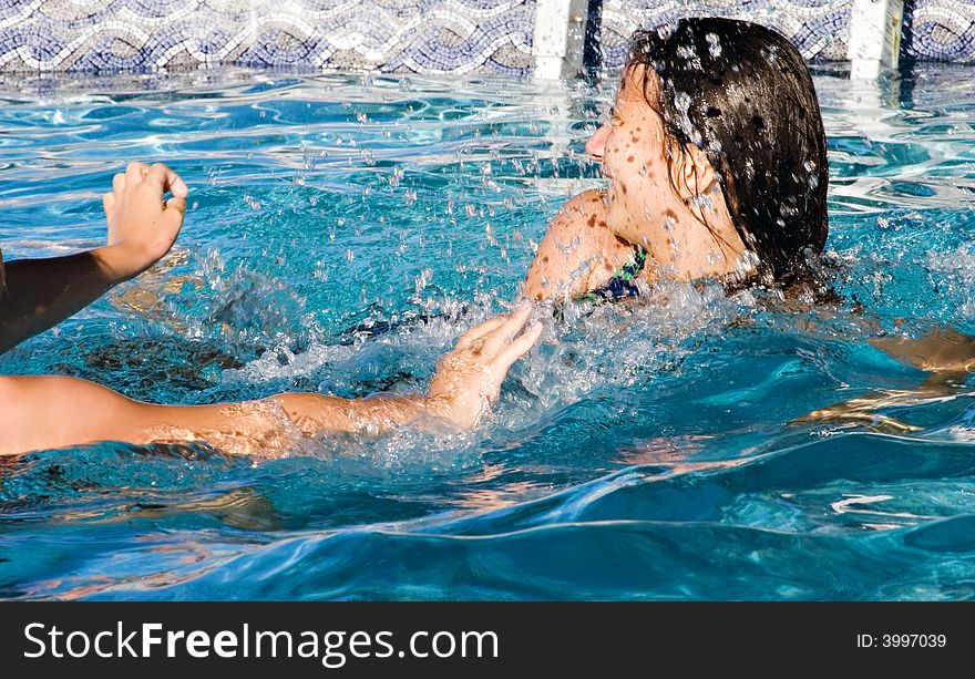 Girls playing and having fun in the swimming pool. Splashes of water. Girls playing and having fun in the swimming pool. Splashes of water.