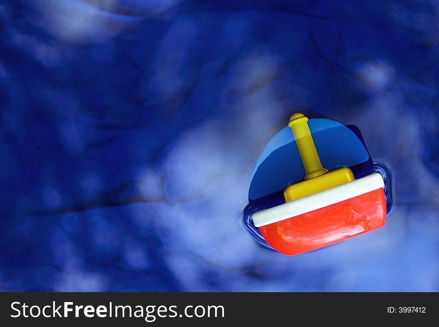 A color photograph of a toy ship in water. A color photograph of a toy ship in water.