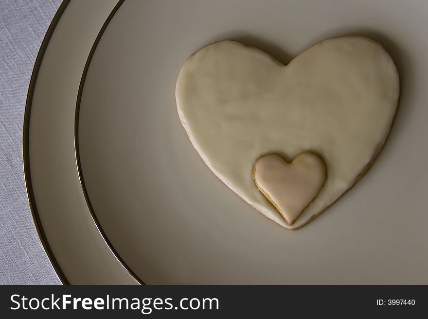 Hand made and decorated heart shaped cookie on china plates. Hand made and decorated heart shaped cookie on china plates.