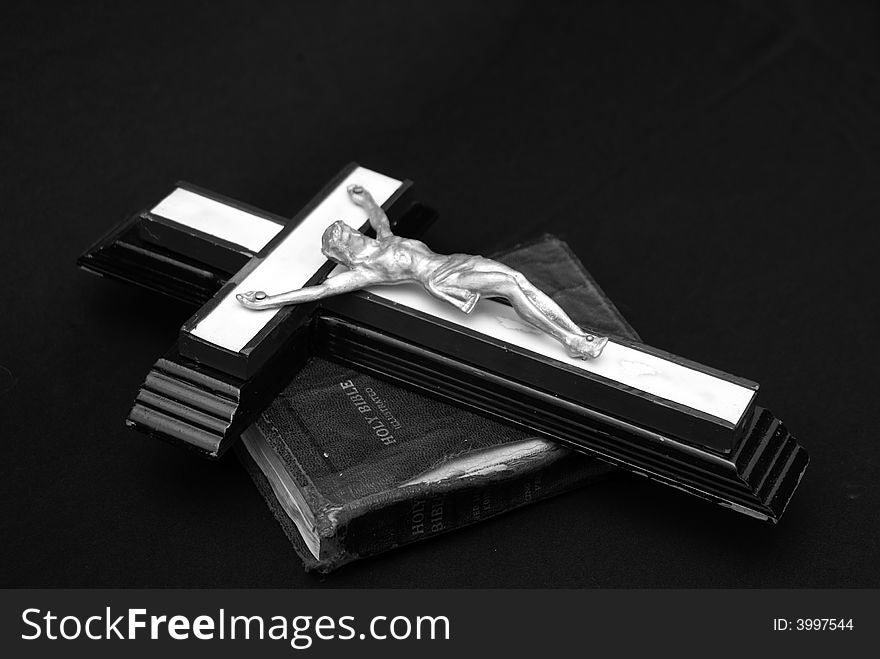 Striking black and white image of an old crucifix laying on top of an ancient leatherbound bible. Striking black and white image of an old crucifix laying on top of an ancient leatherbound bible