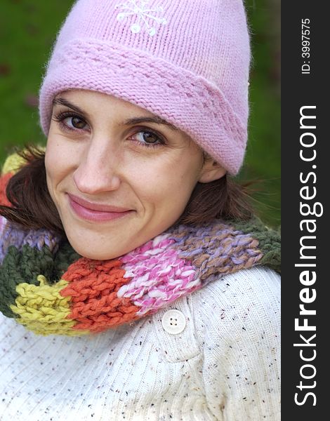 A beautiful woman wearing a multi-color scarf, sitting on a bench, and wearing a bonnet. A beautiful woman wearing a multi-color scarf, sitting on a bench, and wearing a bonnet.