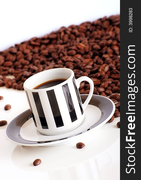 Some coffee beans behind a cup of black coffee on white background. Some coffee beans behind a cup of black coffee on white background