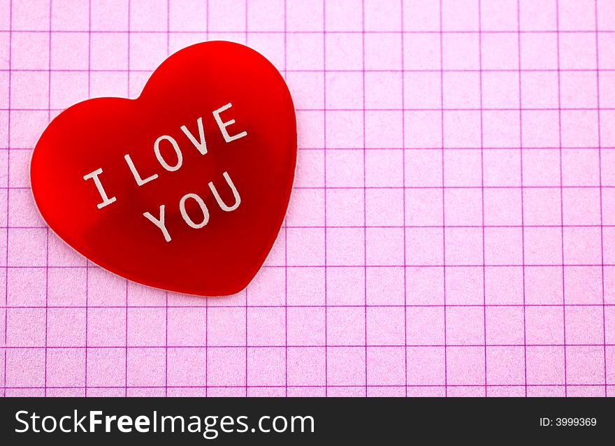 Red heart with I Love You message on pink chequered sheet of paper with copy space. Red heart with I Love You message on pink chequered sheet of paper with copy space