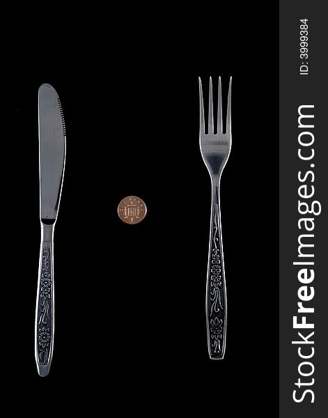 One penny lying between fork and knife. One penny lying between fork and knife