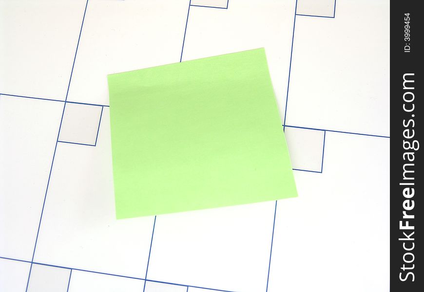 Green sticky note on surface of blank calendar